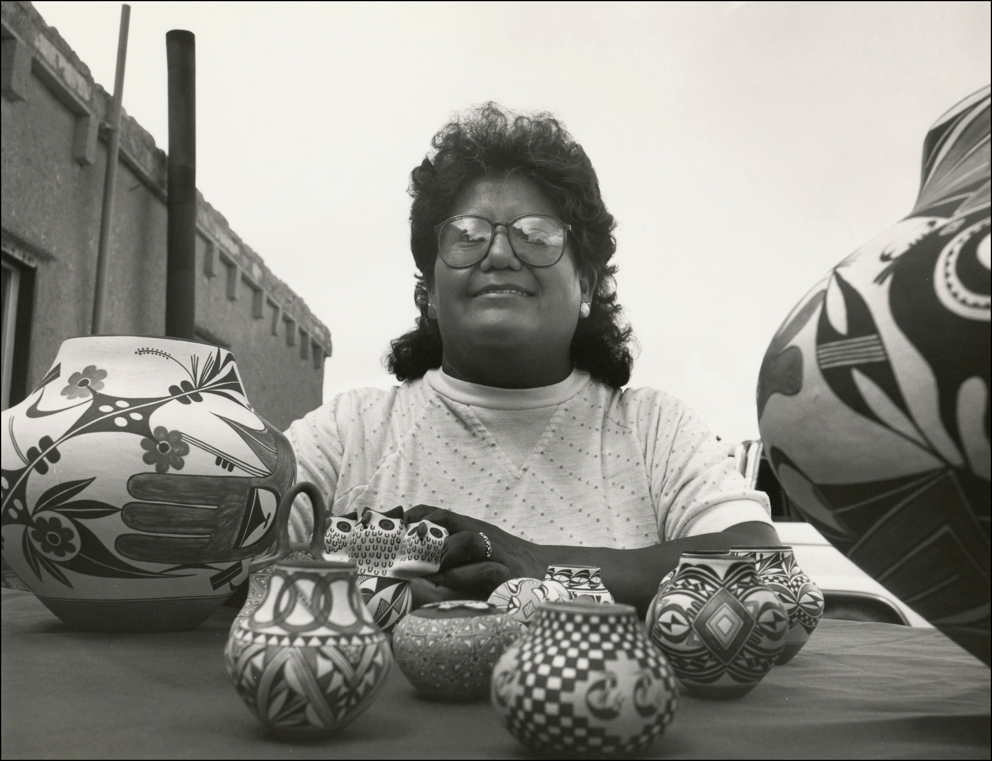 Native woman sitting at a table selling her handmade pottery